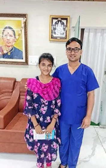 Dr. Sridhar in surgical scrubs with a young patient